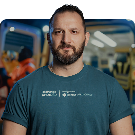 Boris Schweizer vor Rettungswagen mit Primus Medicinae-Shirt.