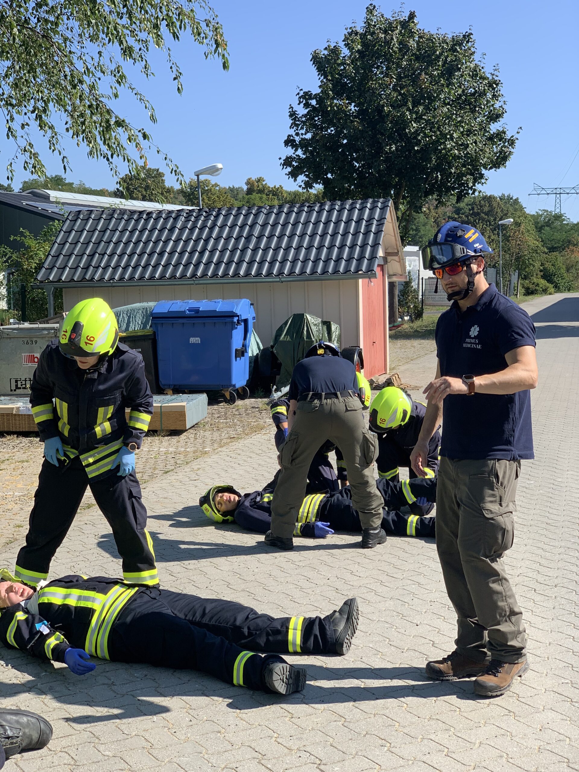 Katastrophenübung: Personen in Feuerwehreinsatzkleidung, einige liegen auf dem Boden und werden behandelt.